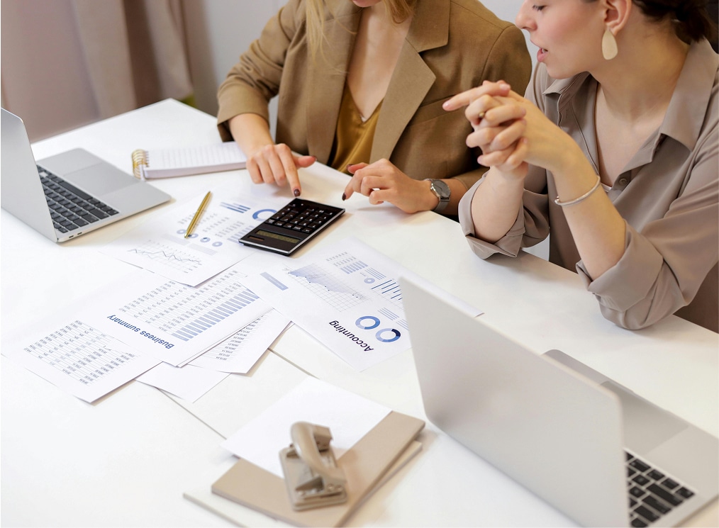 Two women working with laptops and calculator on financial accounting documents